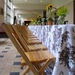 Country Picnic themed table display with wooden chairs, floral linens, potted sunflowers and garden florals